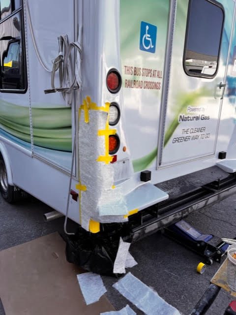 Fiberglass reconstruction in progress on a commercial shuttle bus after collision damage