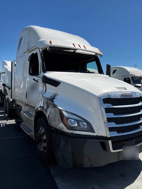 Freightliner Cascadia sleeper tractor with rollover damage to the cab, hood and passenger side before repair in Las Vegas
