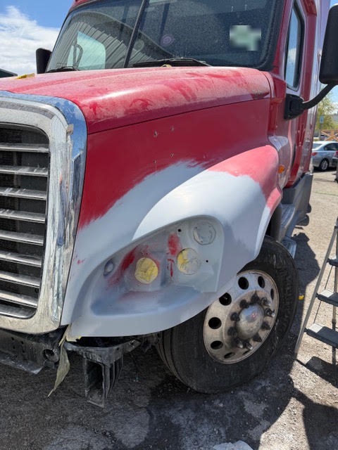 Freightliner Cascadia fiberglass hood in primer with the rebuilt headlight pocket masked before refinishing