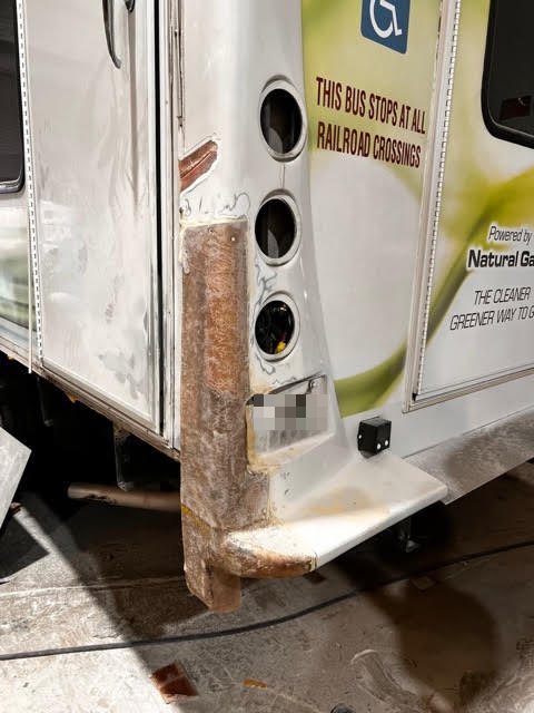 Heavy-duty fiberglass reconstruction on the rear corner of a commercial shuttle bus