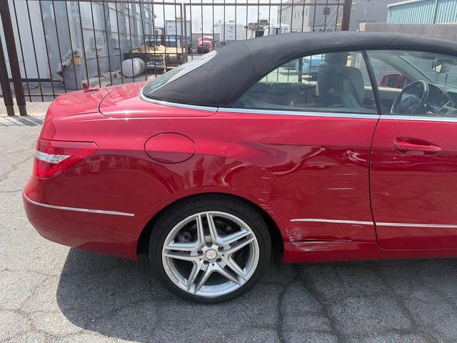 Scuffed rear quarter panel on a red Mercedes-Benz E-Class convertible before paint repair in Las Vegas