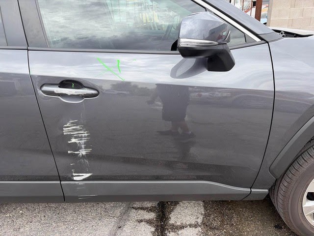 Deep scrape and gouge damage across the driver's door of a grey Toyota RAV4 before repair in Las Vegas